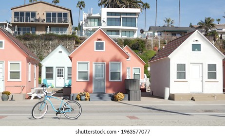 Blue bicycle, cruiser bike by ocean beach, pacific coast, Oceanside California USA. Summertime vacations, sea shore. Vintage cycle by beachfront house, waterfront cotteges, bungalow huts and palm tree