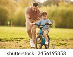 Blue bicycle, riding. Happy father with son are having fun on the field at summertime.