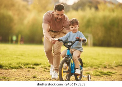 Blue bicycle, riding. Happy father with son are having fun on the field at summertime. - Powered by Shutterstock