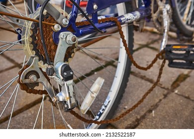 Blue Bike Has Been Outside All Winter And Got Broken. Rusty Bicycle Chain Hangs On Sprocket And Gear.