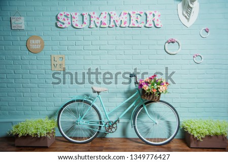 Blue bike on brick wall background. Summer photo zone in the Studio. Wicker basket with artificial flowers on the bike.
