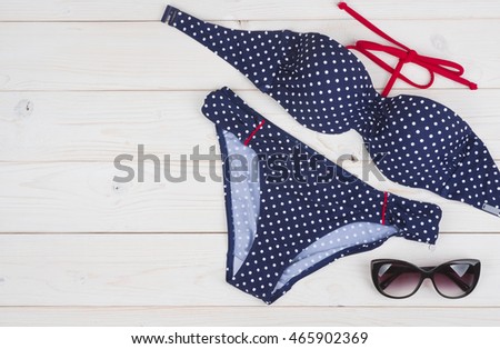 Blue bikini and sunglasses on wooden planks background with copyspace