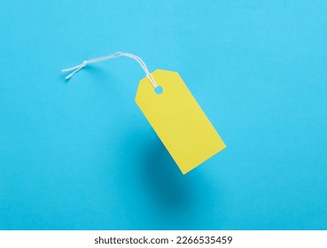 Blue blank clothing price tag or label mockup with string on yellow background. Sale, shopping concept. Top view - Powered by Shutterstock