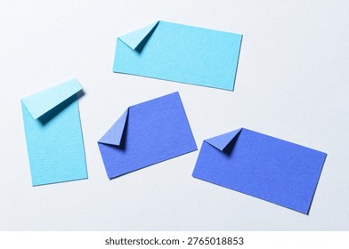 Blue blank paper message notes or sheets with folded edge dog-ear earmark and copy space for text on white background, top view flat lay conceptual desk backdrop