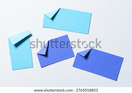 Blue blank paper message notes or sheets with folded edge dog-ear earmark and copy space for text on white background, top view flat lay conceptual desk backdrop