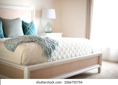 Blue Blanket On The Edge Of A King Size Bed With White Quilt And Linens, And Turquoise Decorative Throw Pillows, And Space For Text On The Right