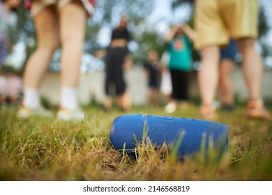 Blue Bluetooth Audio Speaker On The Grass. A Close-up Of A Blue Wireless Music Speaker Standing Among The Dense Green Grass.