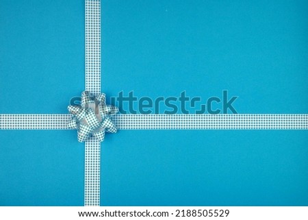 Blue bow and ribbon crossed to decorate gifts, greetings, holidays on a blue background. Background for a postcard.