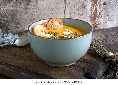 Blue Bowl With Creamy Carrot Soup With Thyme On The Table