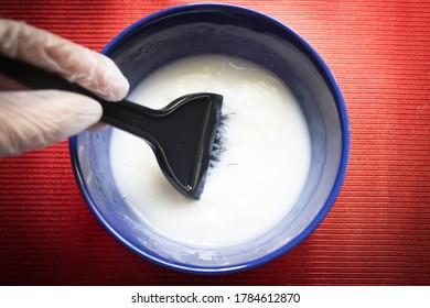 Blue Bowl With Mix To Dye Hair. Womans Hand Removing The Dye Mixture.