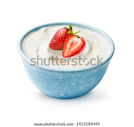 Blue bowl of yogurt with fresh beautiful strawberries isolated on white background. Half and whole strawberry light on fresh yoghurt.