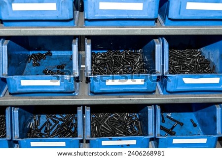 Blue box with small construction storage compartments filled with screws, nuts, bolts workshop tools