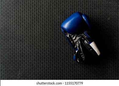 Blue Boxing Glove On Black Rubber Floor In Boxing Gym. 