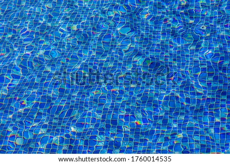 Blue and bright water in mozaic swimming pool with sun reflection background