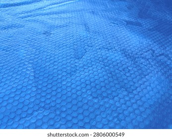 Blue bubble solar pool cover designed to protect outdoor swimming pools from dirt, leaves, and debris while helping retain water temperature. Durable thermal pool blanket for efficient pool maintenance, energy savings, and cleaner water.