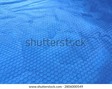 Blue bubble solar pool cover designed to protect outdoor swimming pools from dirt, leaves, and debris while helping retain water temperature. Durable thermal pool blanket for efficient pool maintenance, energy savings, and cleaner water.