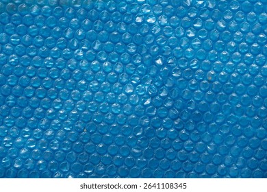 Blue bubble wrap texture with a smooth, glossy surface. The bubbles are evenly spaced, creating a uniform pattern. Ideal for backgrounds and abstract designs.