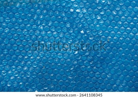 Blue bubble wrap texture with a smooth, glossy surface. The bubbles are evenly spaced, creating a uniform pattern. Ideal for backgrounds and abstract designs.