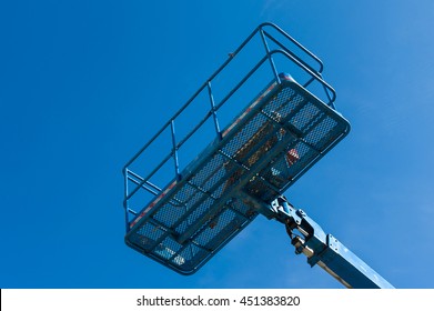 Blue Bucket Of Cherry Picker Against Blue Sky.