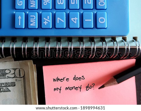 Blue calculator, cash money, pencil, pink note with text written WHERE DOES MY MONEY GO?, concept of find out spending leaks to fix them and boost saving
