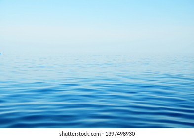 A blue calm sea connects to the horizon of a blue sky. Beautiful natural background, seascape, summer, travel, vacation. Image - Shutterstock ID 1397498930