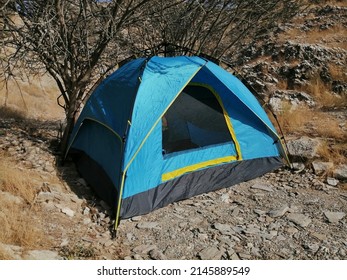 Blue Camping Tent In Rugged Desert Terrain. Wild Camping (off The Grid) And Extreme Outdoor Adventure Concept.