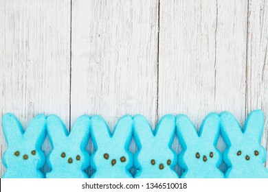 Blue candy bunnies on weathered whitewash textured wood background with copy space for your Easter message