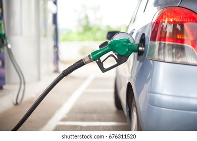 blue car and fuel nozzle in gas station