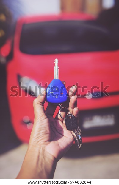 Blue Car key lock. woman Hand presses on\
the remote control car alarm systems.Cross processing.Auto\
insurance business.Car security lock  system\
concept.