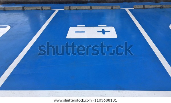 Blue car park and white symbolic of battery on\
the floor, car park in the garage for service to car about Repair\
or change battery.