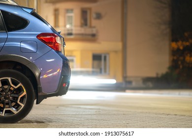 Blue Car Parked On Brightly Illuminated City Street At Night.