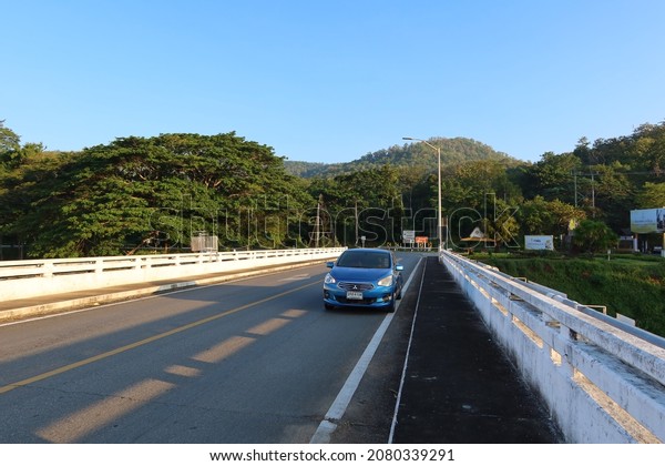 Blue car parked on\
cement bridge in the middle of the road rural travel Nakhon Sawan\
Thailand 13 Nov 2021