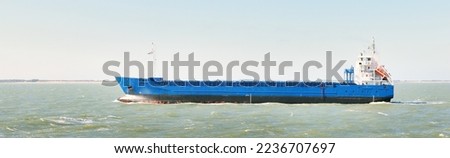 Blue cargo ship sailing to Antwerp port by the coast of Vlissingen, Netherlands. Freight transportation, nautical vessel, logistics, industry, commerce, environment. Panoramic view, copy space