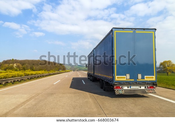 Blue cargo truck on an\
empty freeway