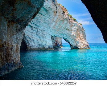 Blue Caves Rock Arces Arches Of Blue Caves From Sightseeing Boat With Tourists In Blue Water Of Ionian Sea Inside Cave, Island Zakynthos, Greece Holidays Vacation Tour. Trip From Agios Nikolaos Port