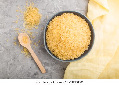 Blue ceramic bowl with raw golden rice and wooden spoon on a gray concrete background and yellow textile. Top view, flat lay, close up. - Powered by Shutterstock