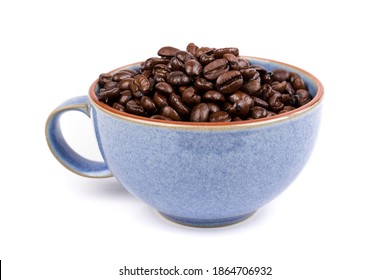 Blue ceramic cup filled with brown roasted coffee beans isolated over white