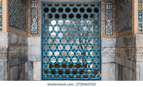 Blue ceramic window screen with hexagonal lattice pattern. View through the geometric mosaic grille of an ancient Islamic building in Samarkand