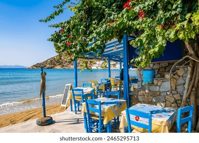 Blue chairs and tables in traditional Greek taverna restaurant on sandy beach in Platis Gialos village, Sifnos island, Greece - Powered by Shutterstock