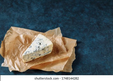 Blue Cheese On A Parchment Paper. Dark Textured Background