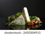 Blue cheese with walnuts and fresh greens on a black background.