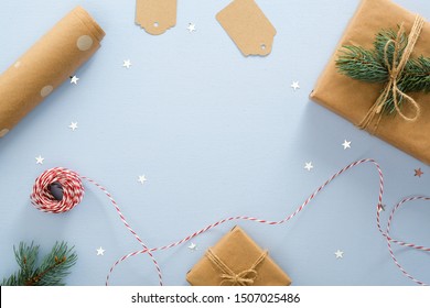 Blue Christmas Background With Gift Box, Fir Tree Branch, Clew Of Rope, Wrapping Paper Roll. Christmas, Winter, New Year Concept. Flat Lay, Top View, Overhead.