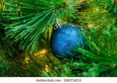 Blue Christmas Ball In The Branches Of A Decorated Christmas Tree. Close-up, Bokeh, Back Drop.