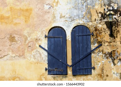 Blue closed shutter doors and golden lantern in colorful weathered wall of National Maritime Museum and old Dutch VOC (United East India Company) building, Galle Fort, Sri Lanka