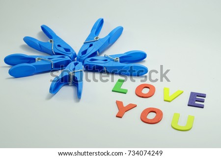  Blue cloth pin arrangement for flower concept with multicolor wood letter LOVE YOU word isolated on white background                                      
