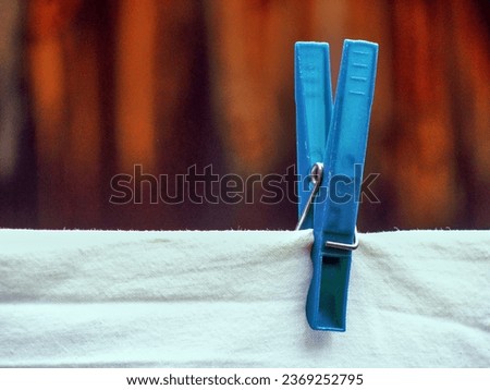 Blue clothes peg holding a white sheet with a wooden background