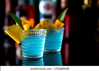 Blue Curaçao Cocktail Garnished With Pineapple  And Orange Pieces Served In A Bar.