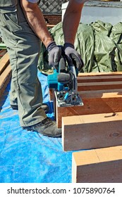 Blue Collar Carpenter Using Electric Saw For Wood Cutting On Site