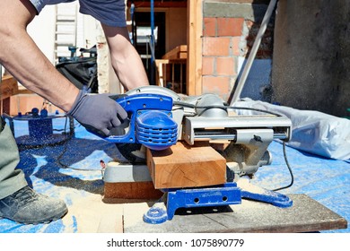 Blue Collar Carpenter Using Electric Saw For Wood Cutting On Site