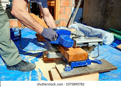 Blue Collar Carpenter Using Electric Saw For Wood Cutting On Site